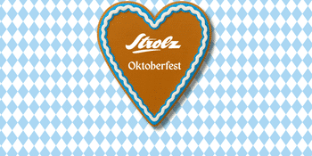 Ein herzförmiger Lebkuchen mit dem Strolz-Oktoberfest-Logo, verziert mit blau-weißer Zuckerglasur. Im Hintergrund ist ein traditionelles bayerisches Rautenmuster in Blau und Weiß zu sehen. Das Motiv vermittelt eine festliche, gemütliche Oktoberfest-Atmosphäre.